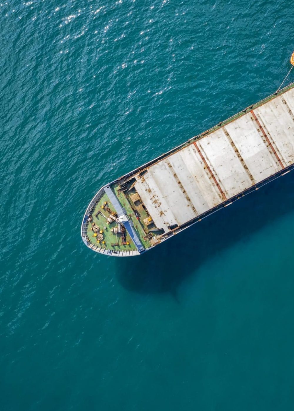 Aerial shot of a cargo ship approaching port with help of towing ship